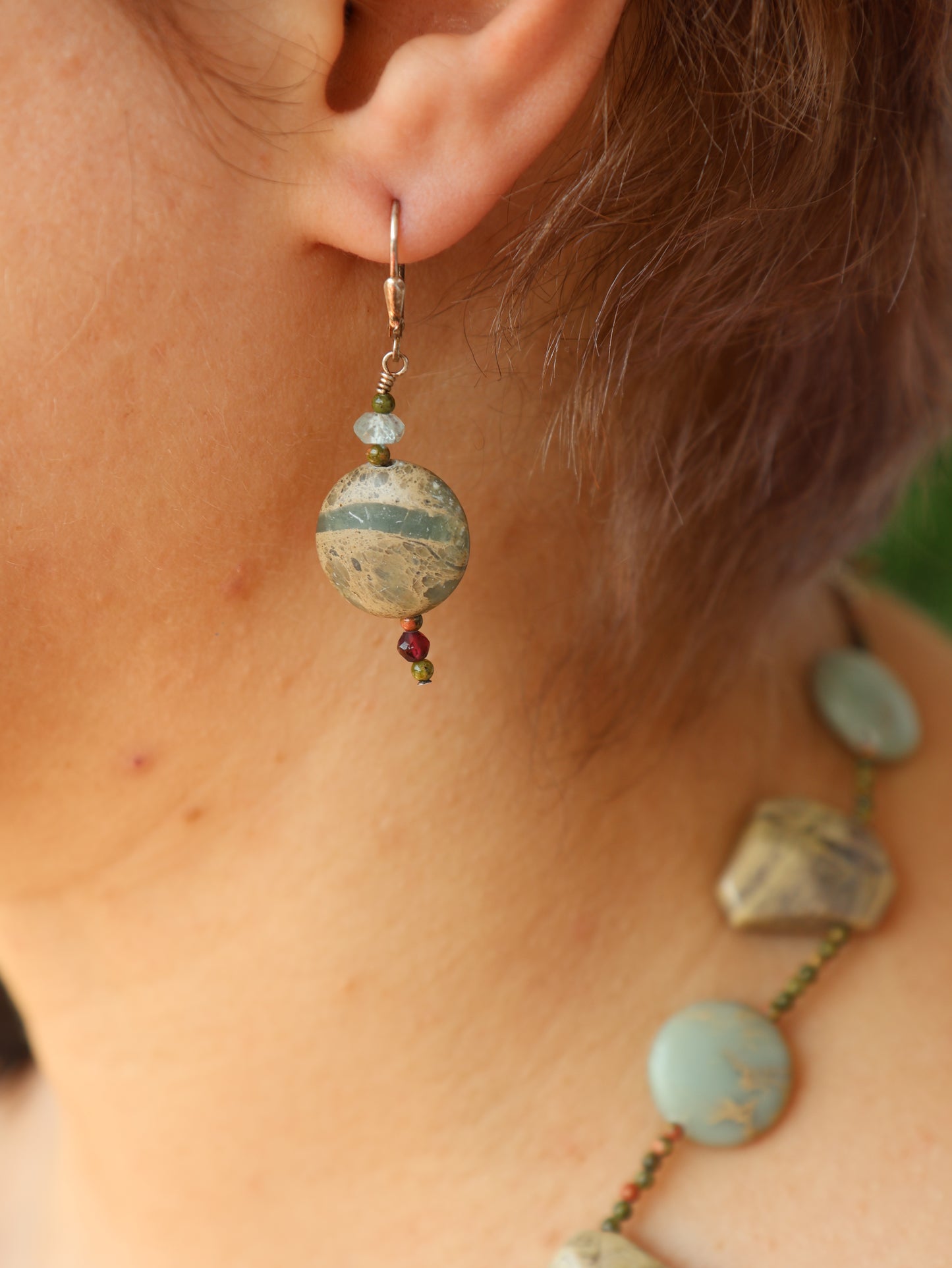 Close-up of an earring with a circular design worn by a person.