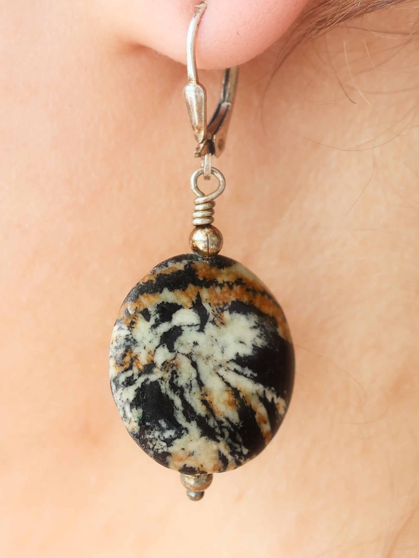 Black marbled stone earring on a person's ear