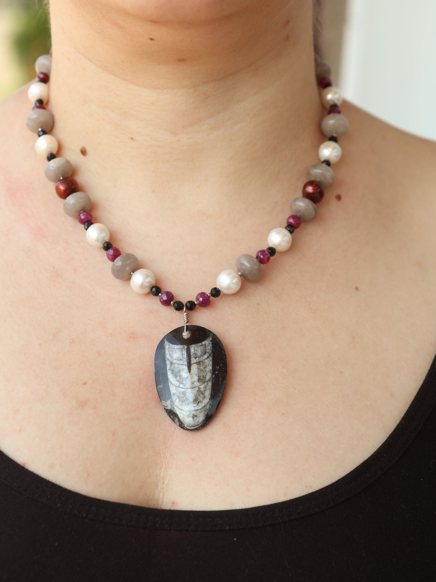 Necklace with a large central stone worn by a person