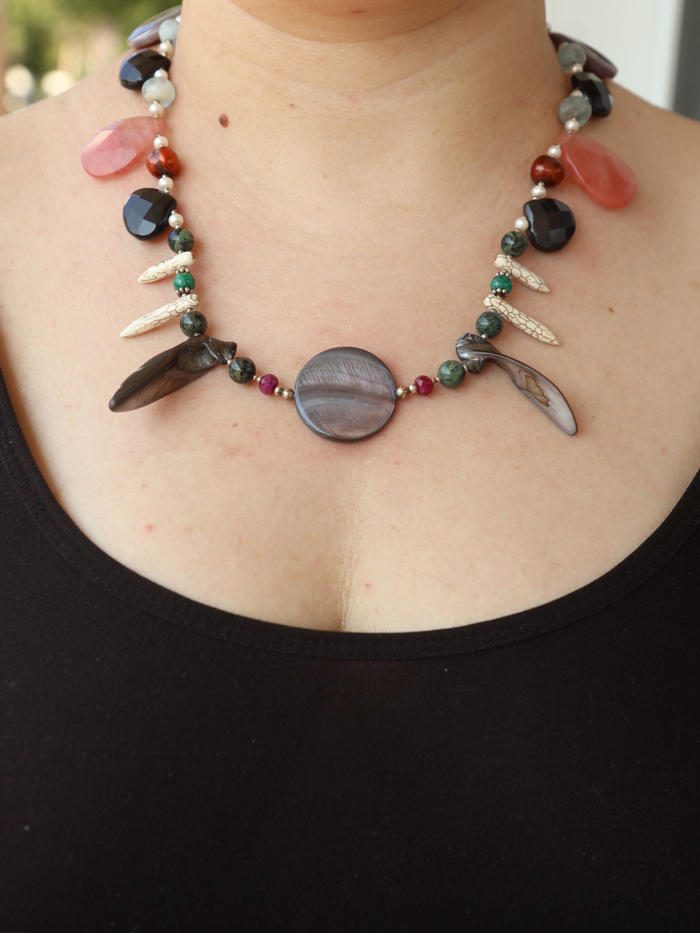 Close-up of a person wearing a colorful beaded necklace with a black background