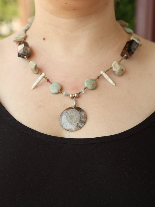 Necklace with natural stone beads worn by a person against a black background