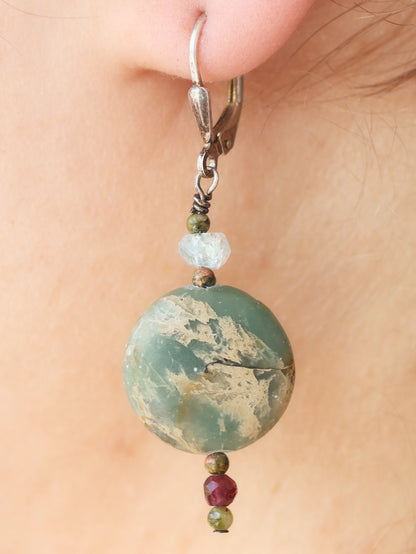 Close-up of a green marbled bead earring with smaller beads on a person's ear.