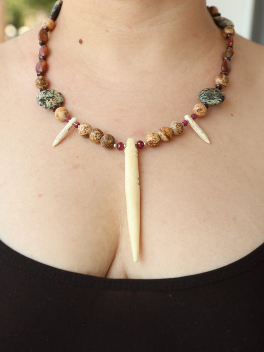 Necklace with beads and bone-like elements on a person's neck against a black background