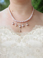 Pearl necklace with dangling beads worn by a person in a white lace garment.