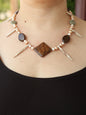 Necklace with stones and pearls on a person wearing a black top.